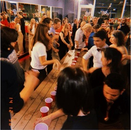 Dance community gathered around a table playing a cup game at last year's VIBE Christmas party.